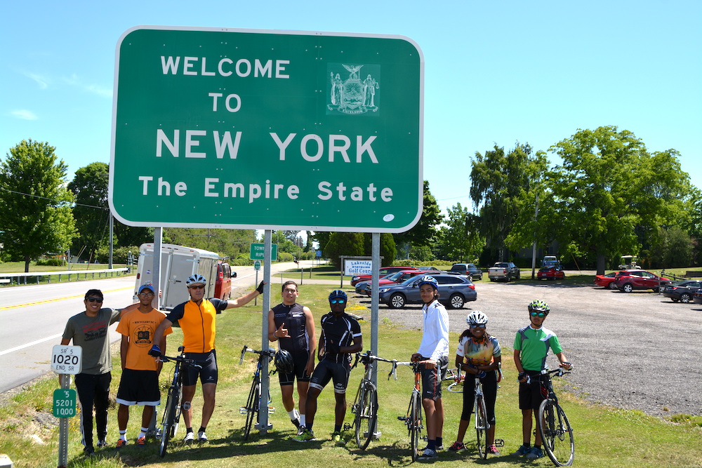 Youth standing under state sign of New York