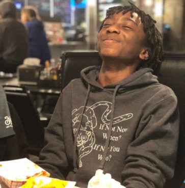 Picture of Solomon sitting in a restaurant booth with his head thrown back in laughter