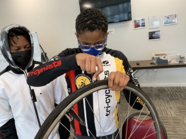 Young girl focused on removing tire from rim to change tube while young boy observes