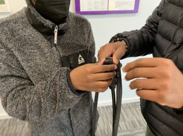 Hands of Triangle Bikeworks youth working to fix a flattened inner bike tube