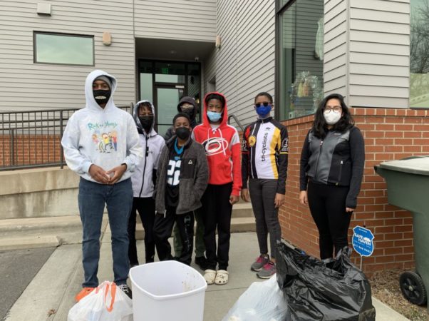 Proud youth standing behind bags of trash cleaned from trail during the MLK Day service