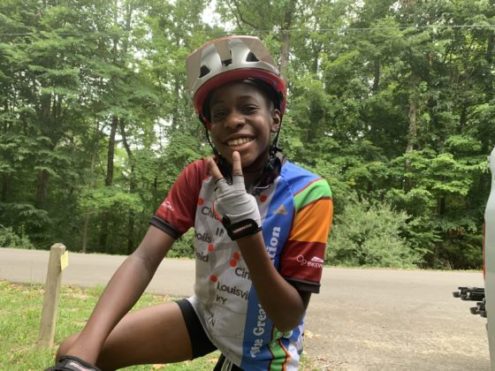young cyclist smiling holding up a peace sign