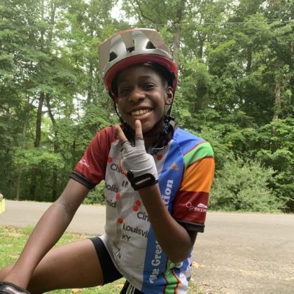 young cyclist smiling holding up a peace sign