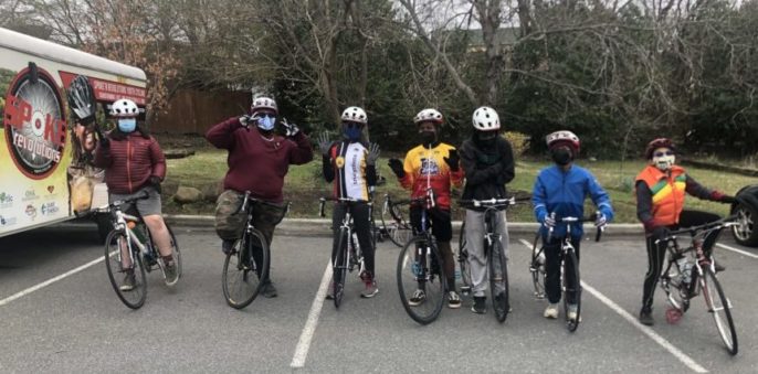 Team of seven youth posing while on bike